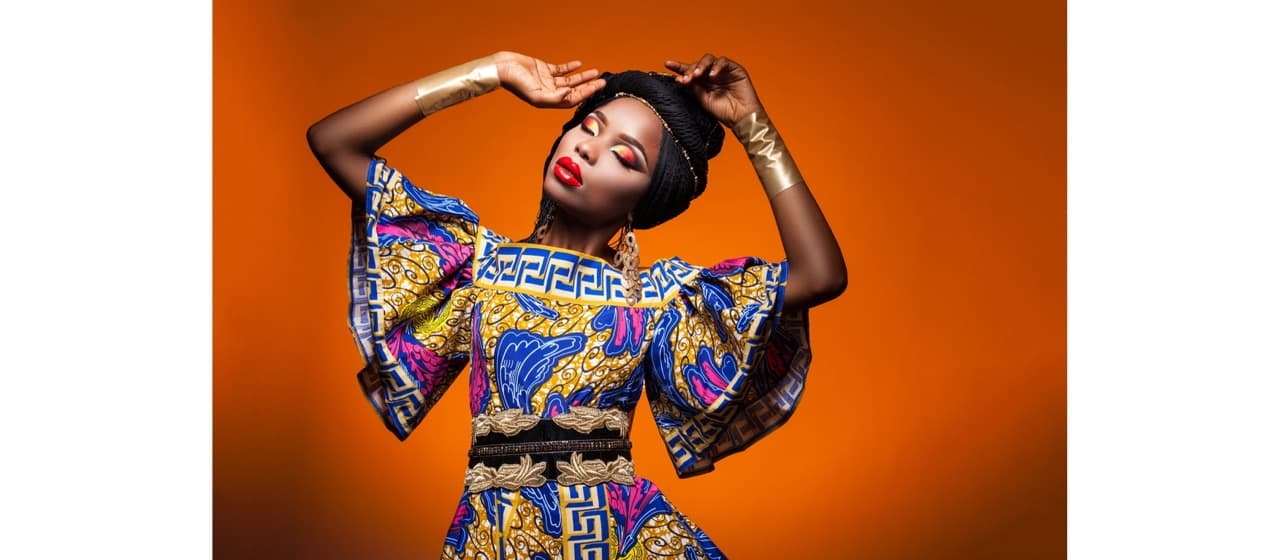 A performer posing against a warm studio backdrop